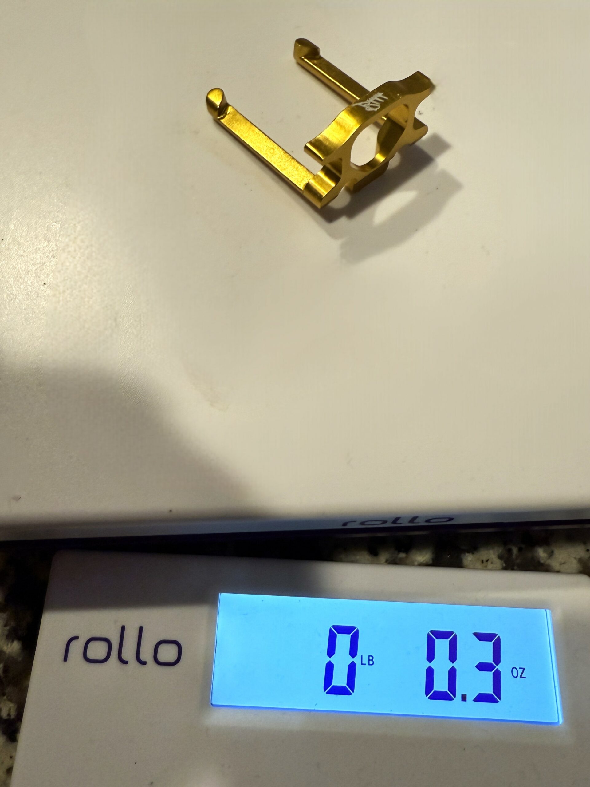 Gunetic Innovations V4 Slip Trip gold anodized aluminum weighing 0.3 ounces on scale